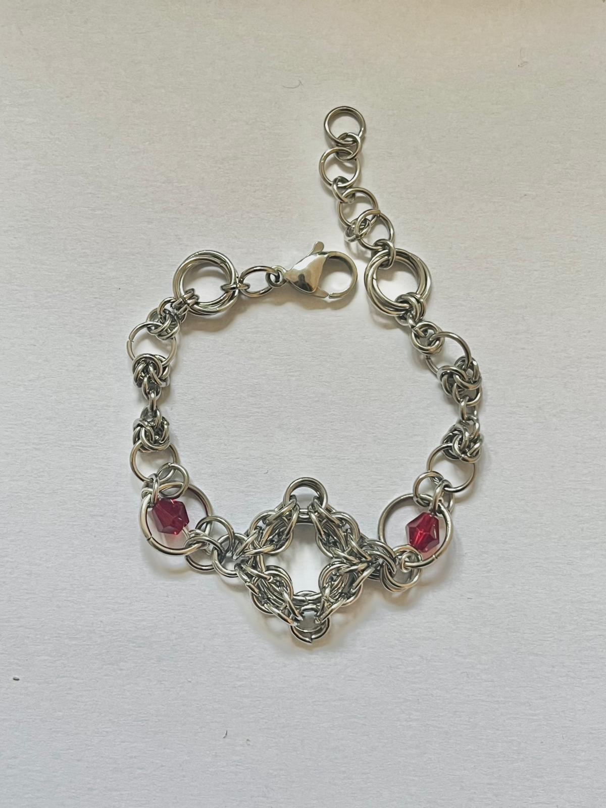 Silver chain bracelet with red gemstones on a white background