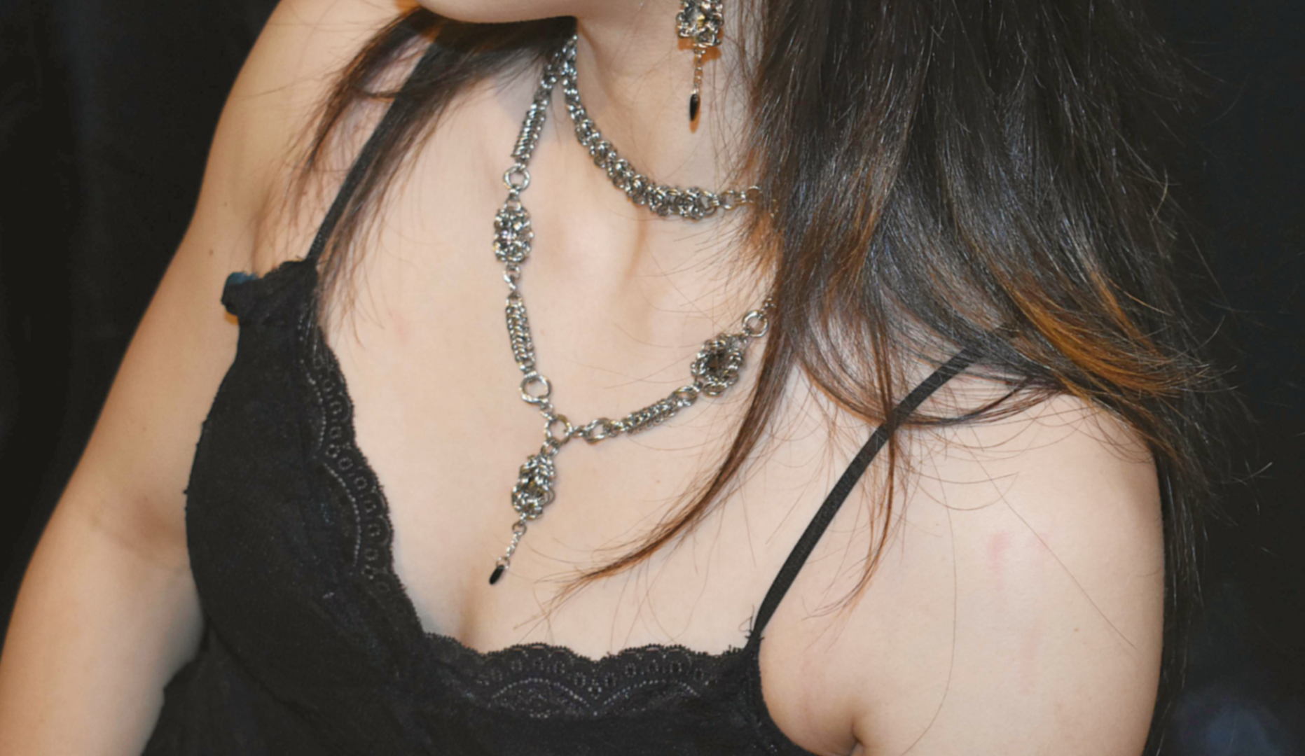 Close-up of a person wearing a black strappy top with a long necklace.