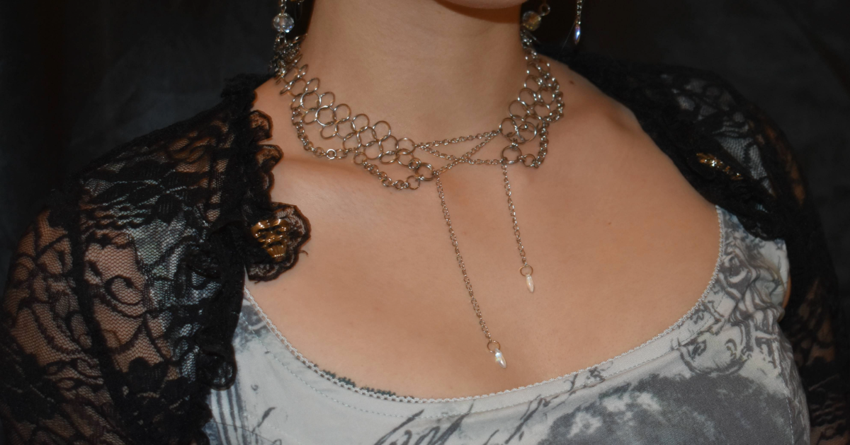 Necklace with chain details on a person wearing a black lace garment.
