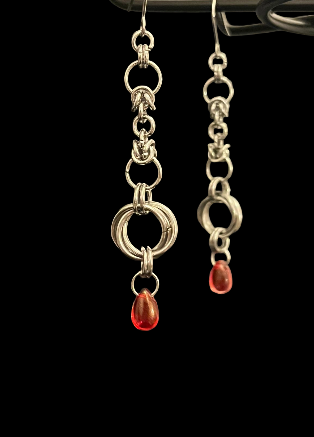 Silver earrings with red gemstones on a black background