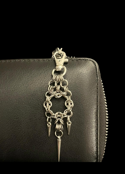 Black leather wallet with a silver chain and spike charm on a black background