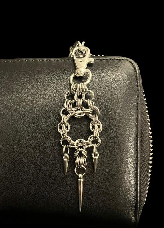 Black leather wallet with a silver chain and spike charm on a black background