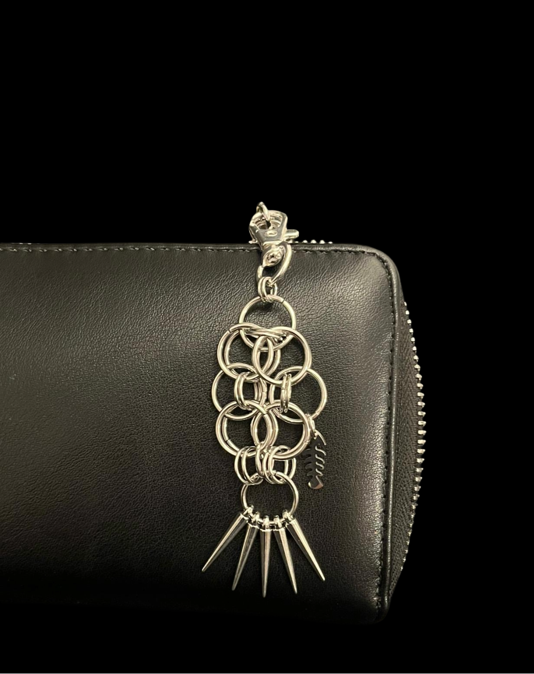 Black leather wallet with a decorative chain and spike charm on a black background