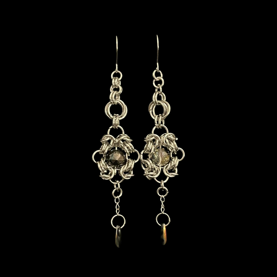 Pair of silver earrings with dangling elements on a black background