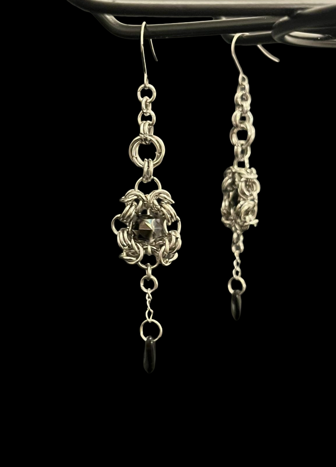 Silver earrings with intricate designs on a black background