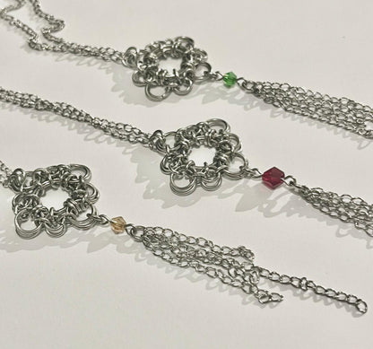 Silver chain necklace with floral designs and beads on a white background