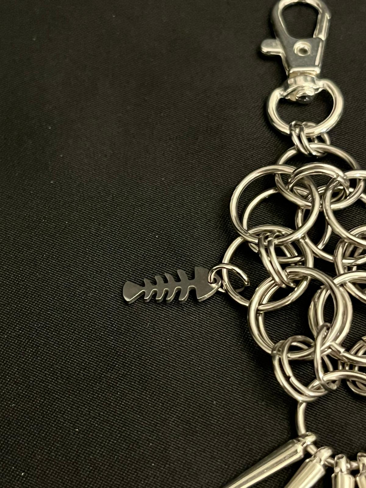 Silver chain keychain with a fish bone charm on a black background