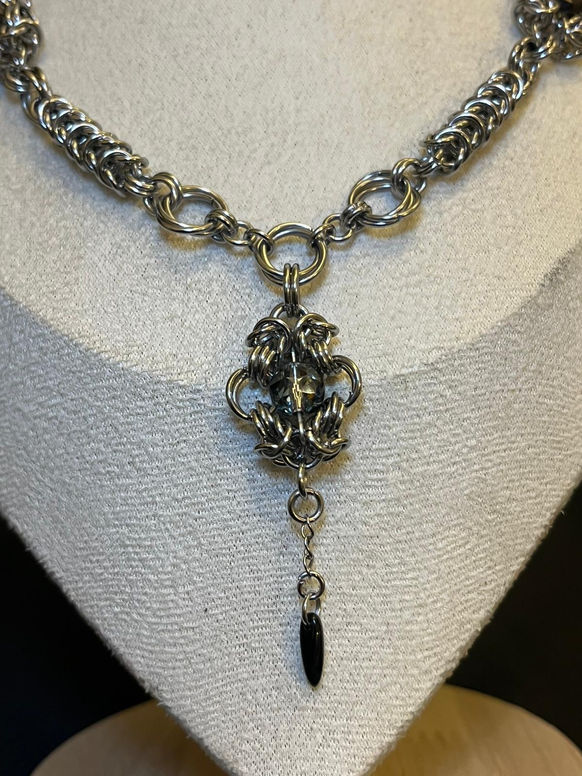 Silver chain necklace with a unique pendant on a mannequin bust.