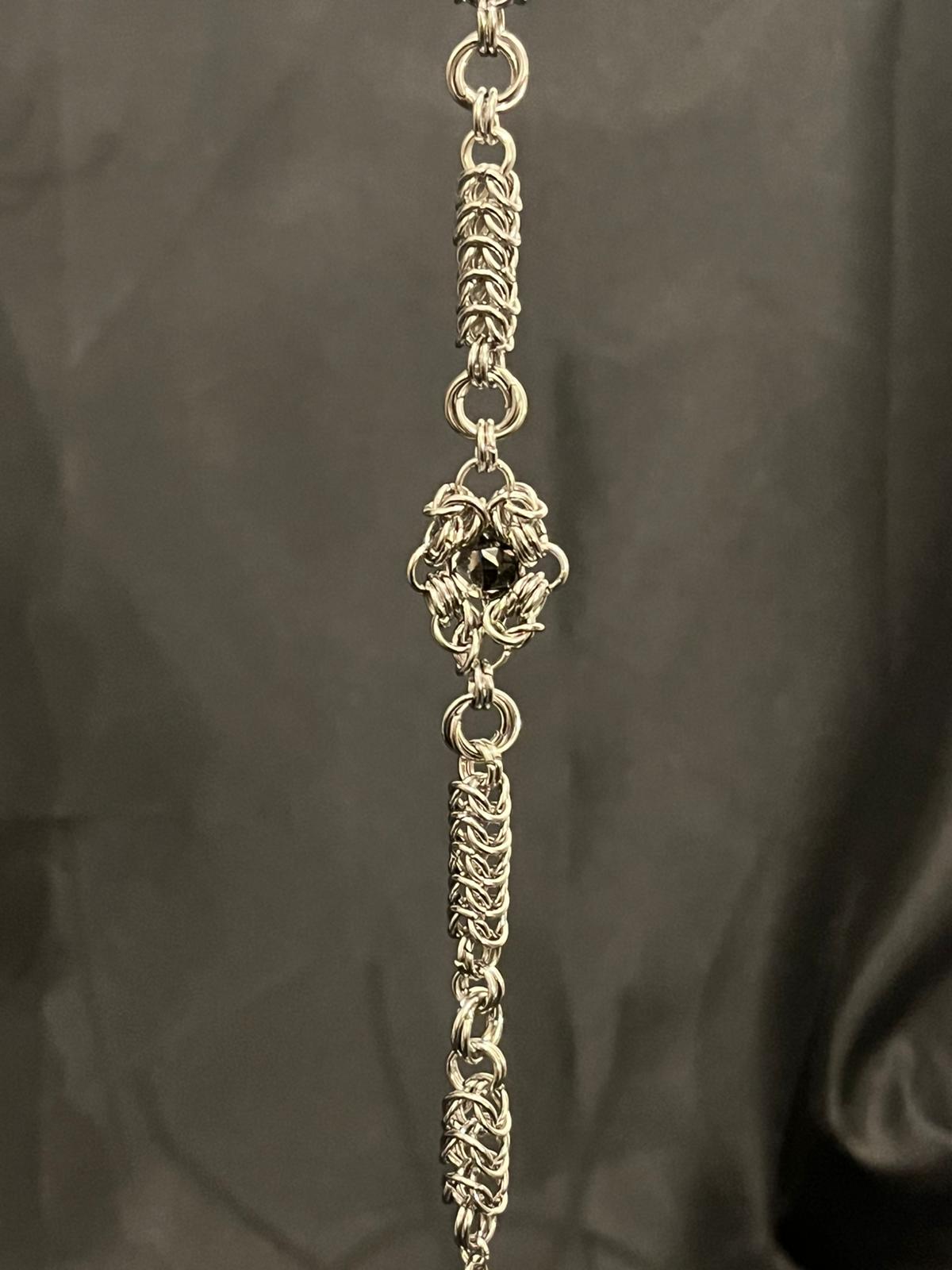 Silver chain necklace with decorative elements on a dark background