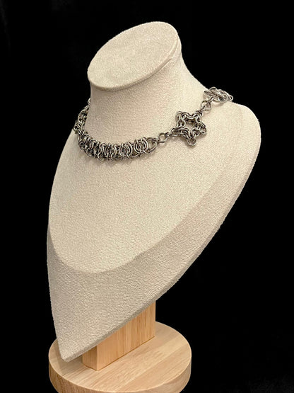 Silver chain necklace on a beige bust with a black background
