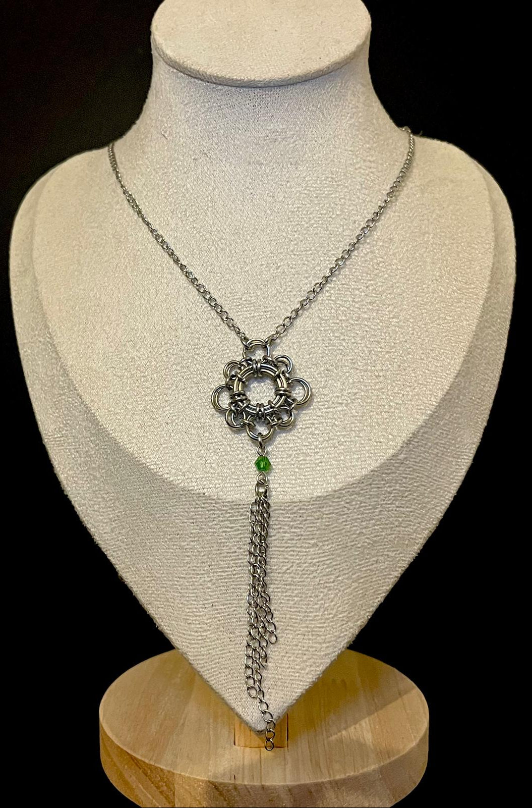 Silver necklace with a decorative pendant on a mannequin bust against a black background