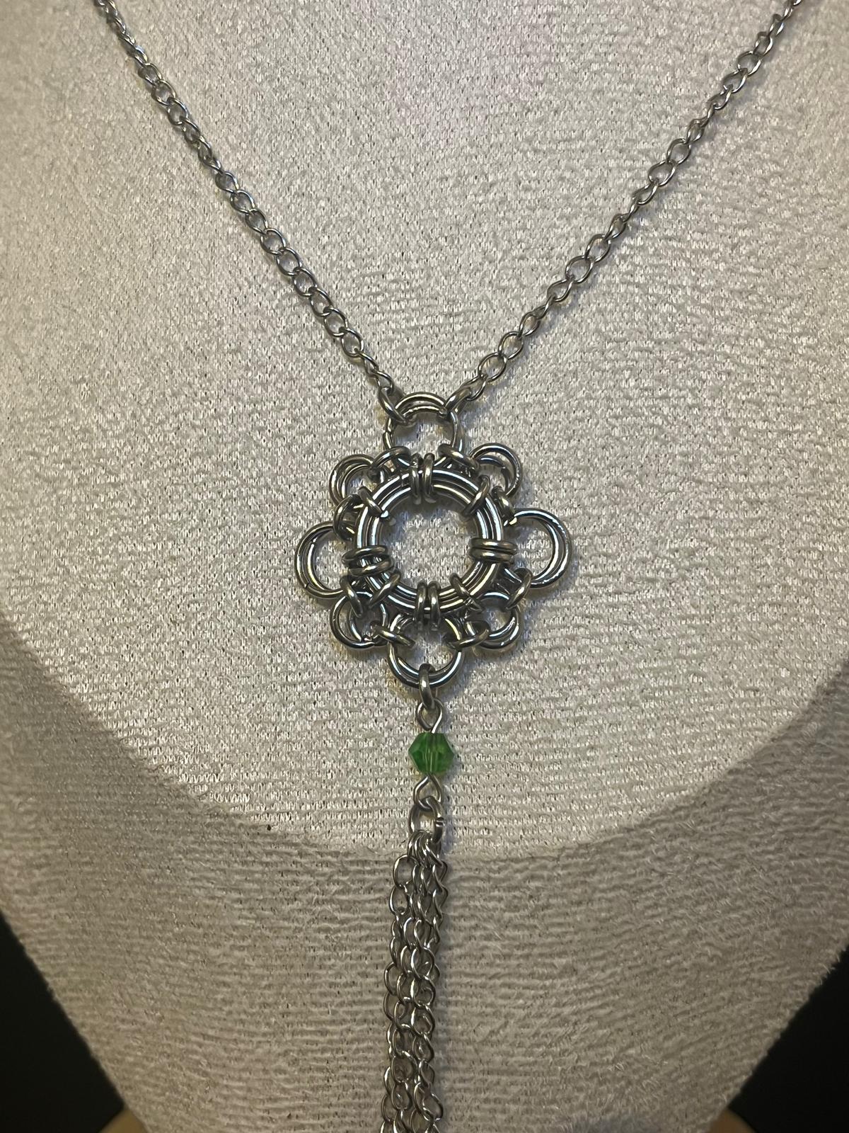 Silver necklace with a decorative pendant on a mannequin bust.