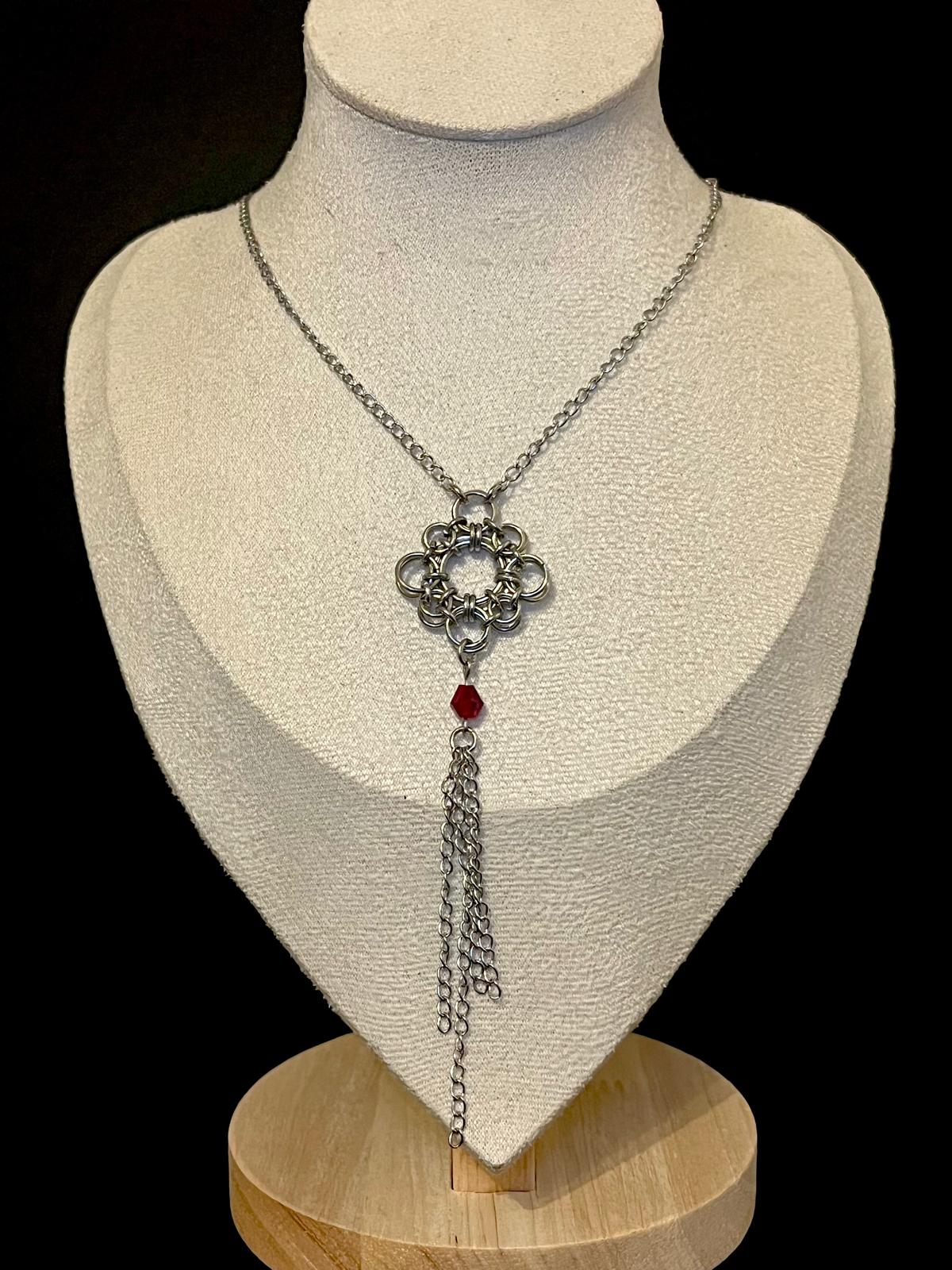 Silver necklace with a red gem on a mannequin bust against a black background