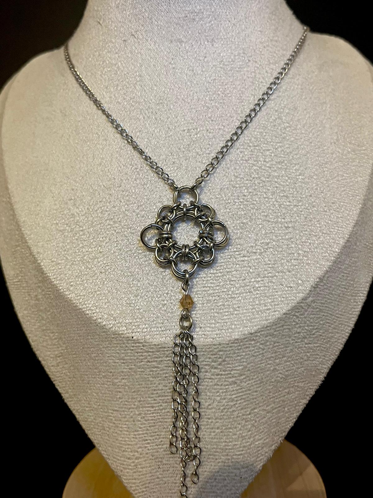Silver chain necklace with a decorative pendant on a mannequin bust.