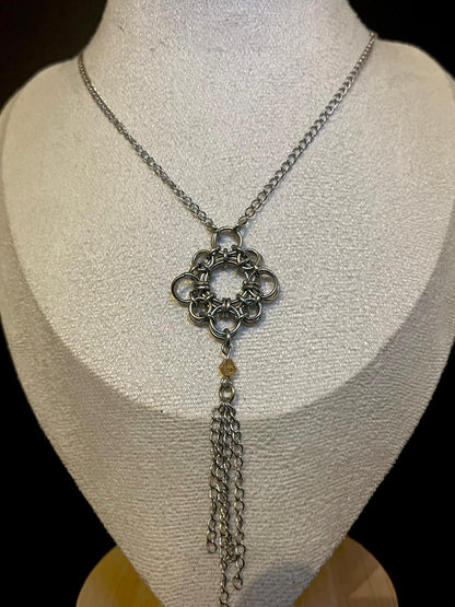 Silver chain necklace with a decorative pendant on a mannequin bust.