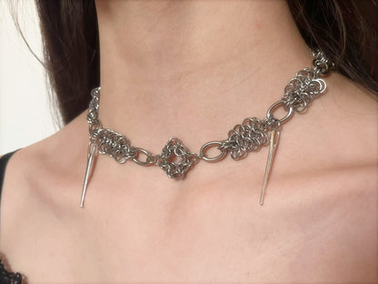 Close-up of a chain necklace with spike-like ends on a person's neck.