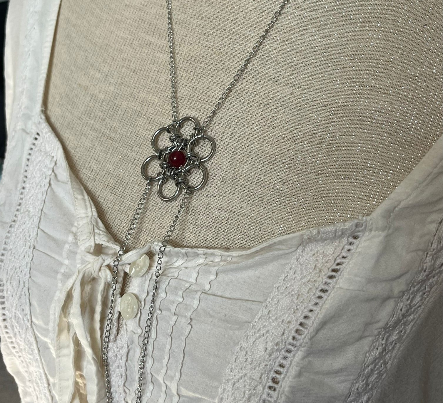 Necklace with a floral design on a mannequin wearing a beige blouse.
