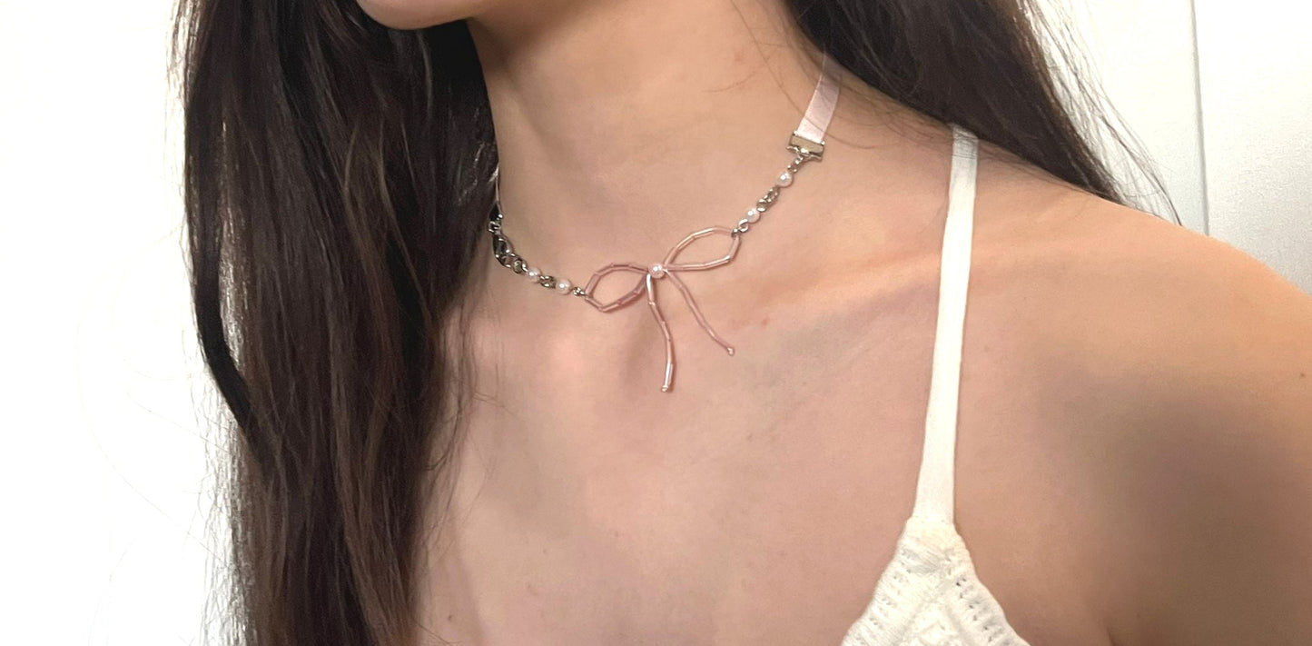 Woman wearing a delicate necklace with a white top against a plain background