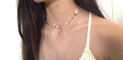 Woman wearing a delicate necklace with a white top against a plain background