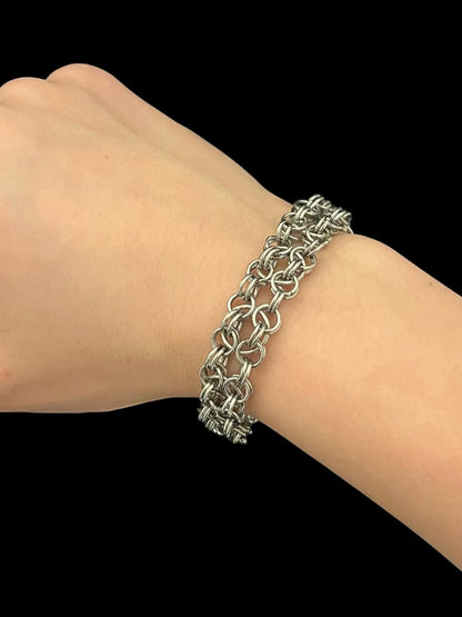 Silver chain bracelet on a wrist against a black background