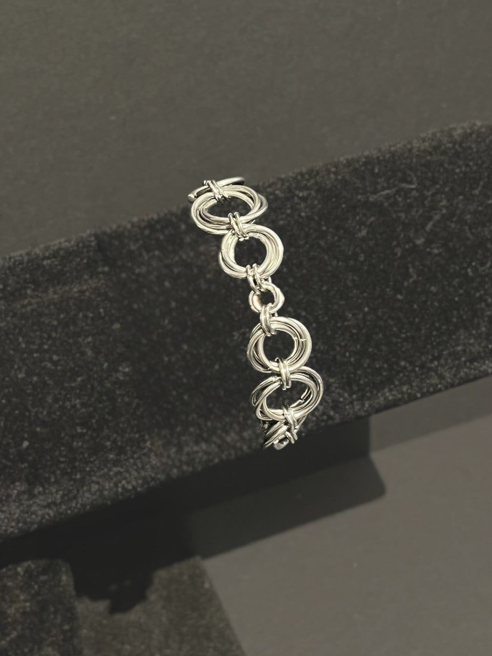 Silver bracelet on a black textured stand