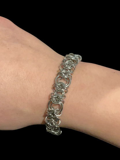 Silver chain bracelet on a wrist against a black background