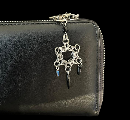 Black wallet with a silver charm on a black background